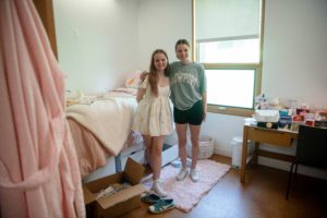 Two girls posing for photo while unpacking items in dorm room_ photo by Holden Blanco '17